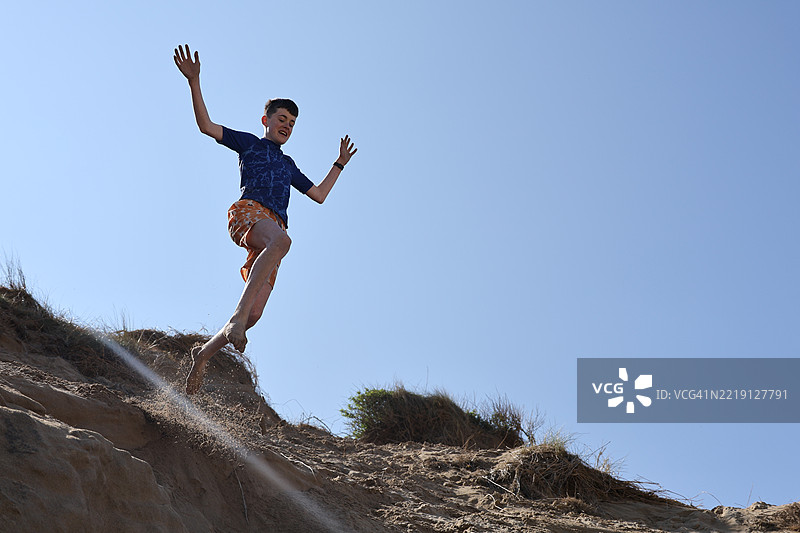 少年从沙丘上跳下图片素材