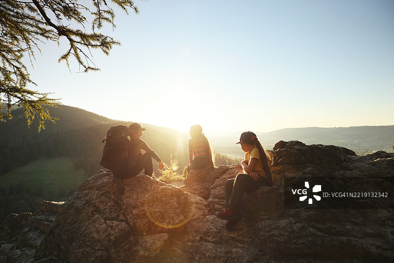 背着背包的父亲与女儿在日落时分坐在山中图片素材