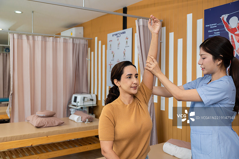 物理治疗师与患者合作。上肢被动运动练习。医生咨询患者的手臂问题，物理治疗概念。竖版视频。图片素材