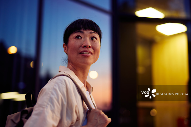 亚洲女商人在日落时分走近办公大楼图片素材