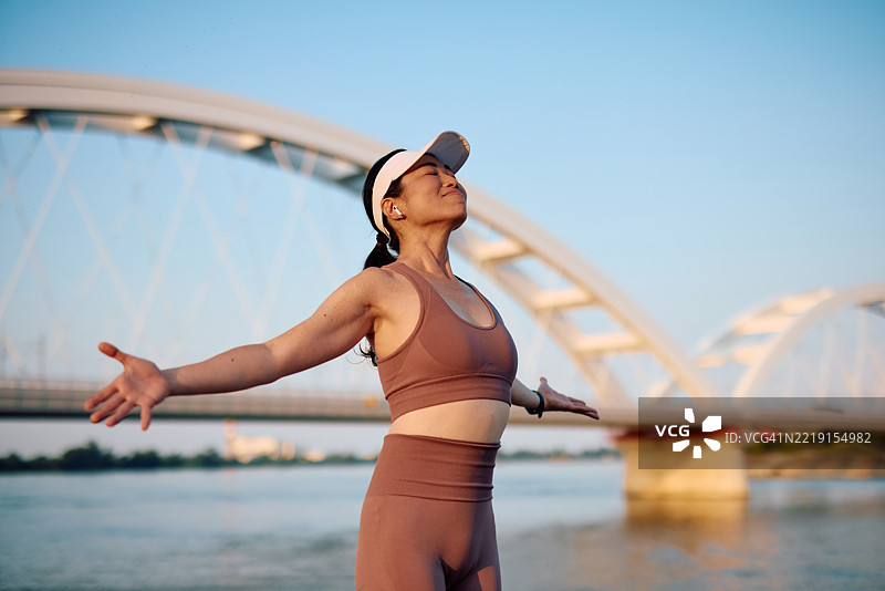 女人在河边享受自由，伸展双臂图片素材