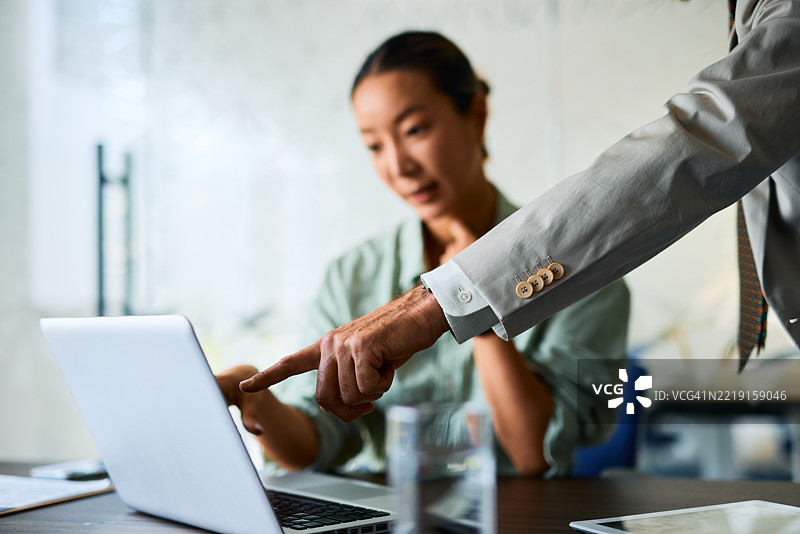 经理在与同事开会时指着笔记本电脑屏幕图片素材