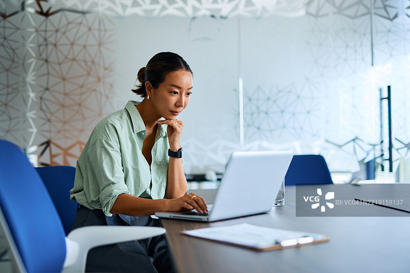 现代办公室中工作的女商人使用笔记本电脑图片素材