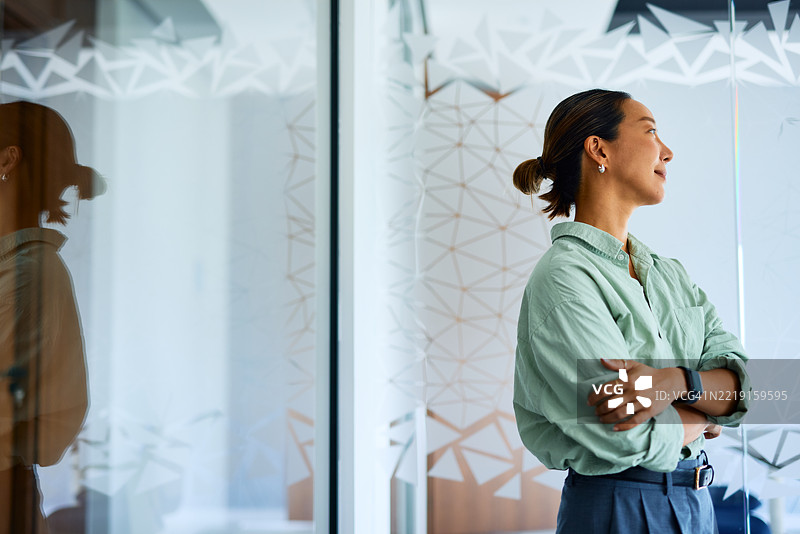 女商人望着办公室窗外，享受成功的喜悦图片素材