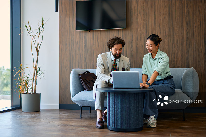 商业伙伴在现代办公室大堂一起使用笔记本电脑工作图片素材