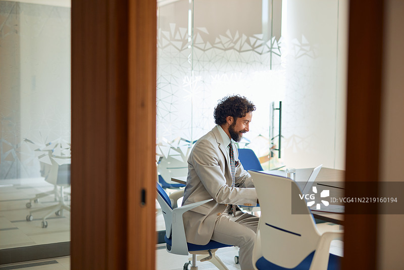 商人在现代办公室会议室内使用笔记本电脑工作图片素材