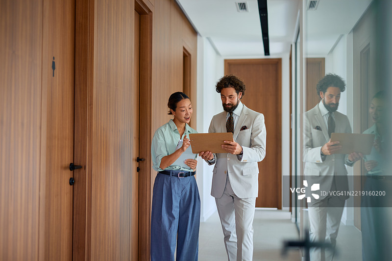 商务人士在办公室走廊中行走并讨论图片素材