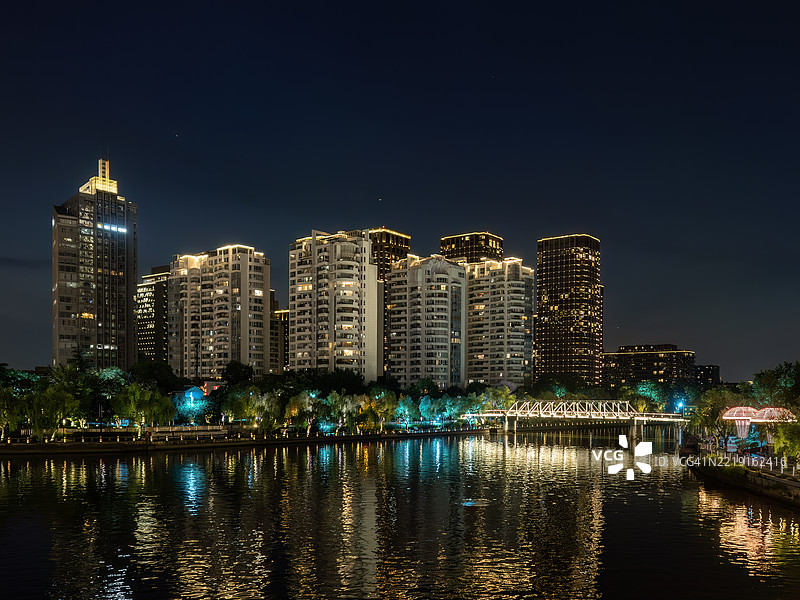夜晚河边的现代公寓楼与棕榈树图片素材