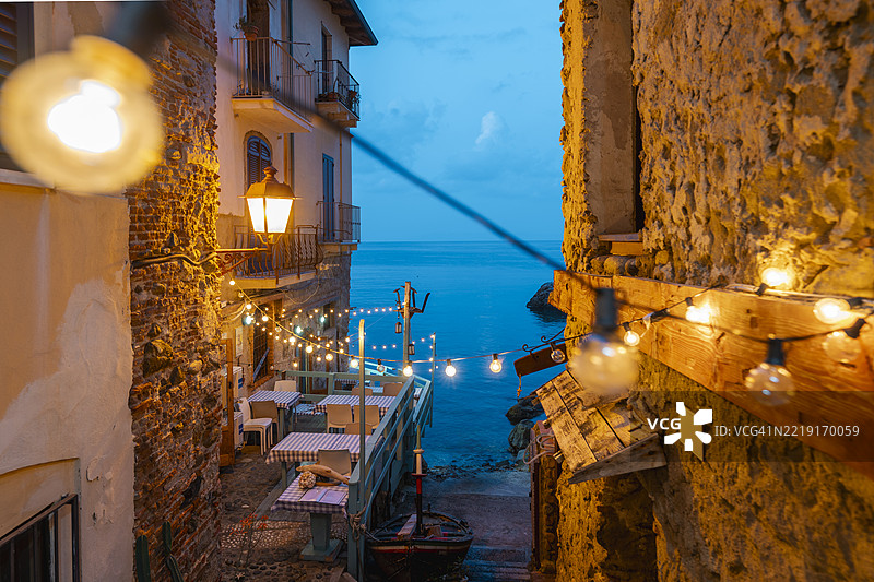 意大利卡拉布里亚的斯基拉，迷人的海滨小巷，灯光璀璨，营造出舒适的户外咖啡馆氛围。图片素材