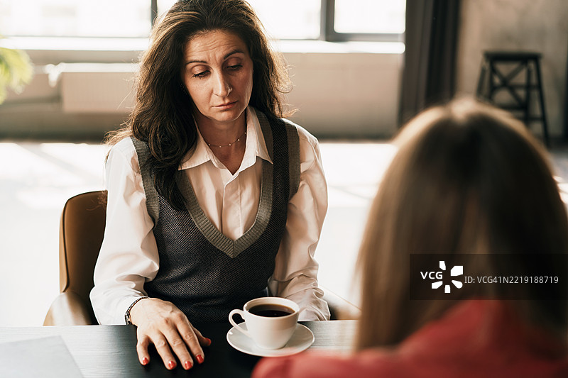 两位女性在温馨的环境中喝咖啡，进行深刻的对话图片素材