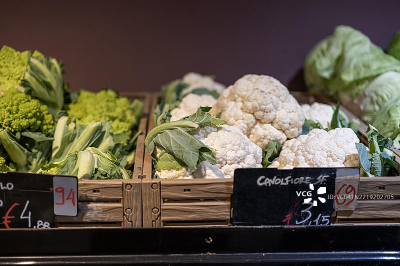 新鲜蔬菜在当地市场的木篮中展示，色彩鲜艳的绿色和白色。图片素材