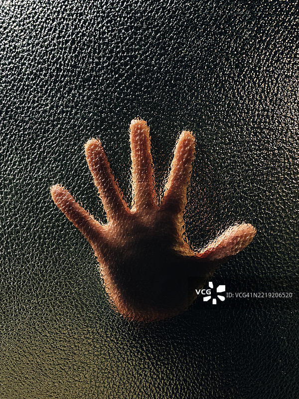 手掌按压在阴影中的纹理玻璃表面图片素材