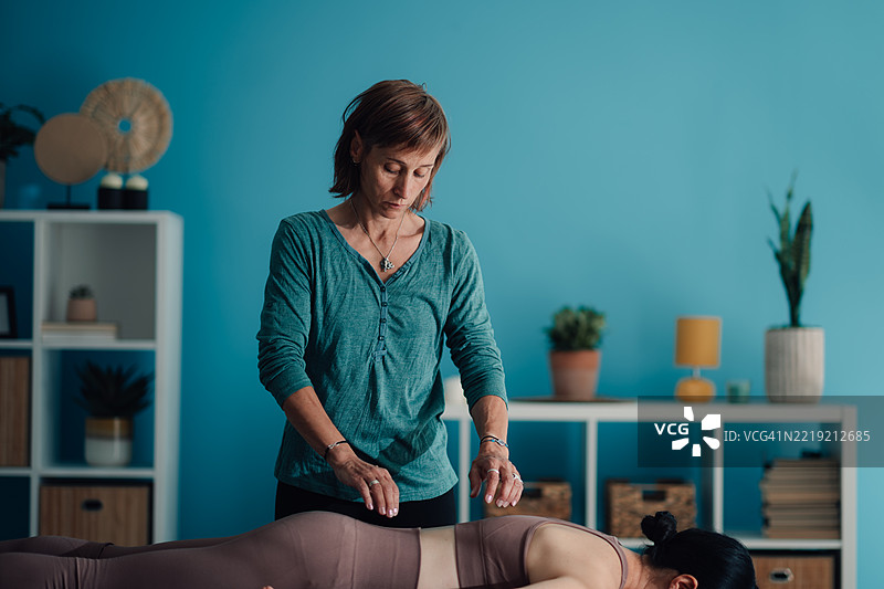 治疗师在按摩床上为躺着的病人进行灵气治疗图片素材