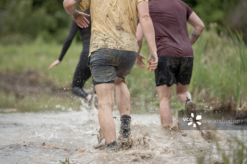 参与者在户外障碍赛中穿越泥泞的水域图片素材