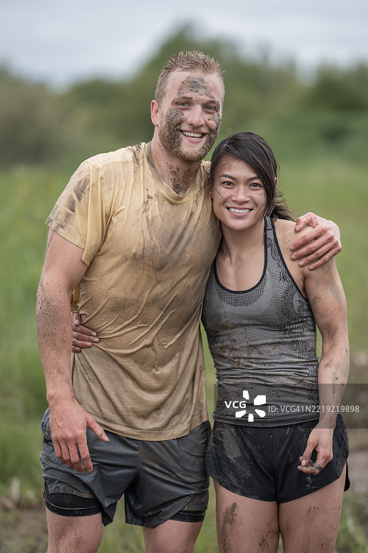 快乐的朋友们在自然环境中完成艰难的泥浆跑后相拥而庆图片素材