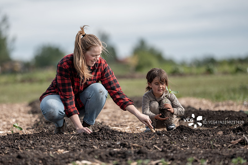 母亲和孩子在阳光明媚的户外花园中一起享受园艺乐趣图片素材