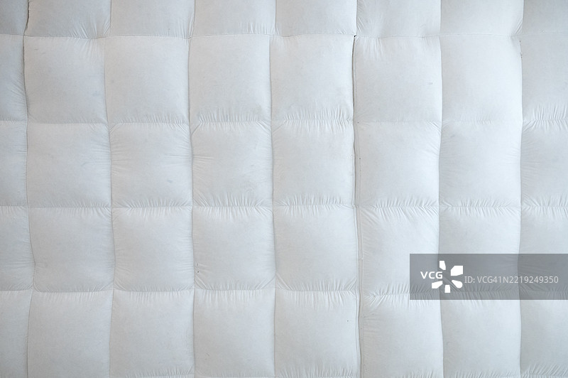 一张白色床和一条白色被子。被子由白色材料制成。图片素材