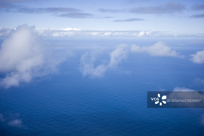 从飞机上俯瞰云朵和蓝色海洋的景色图片素材