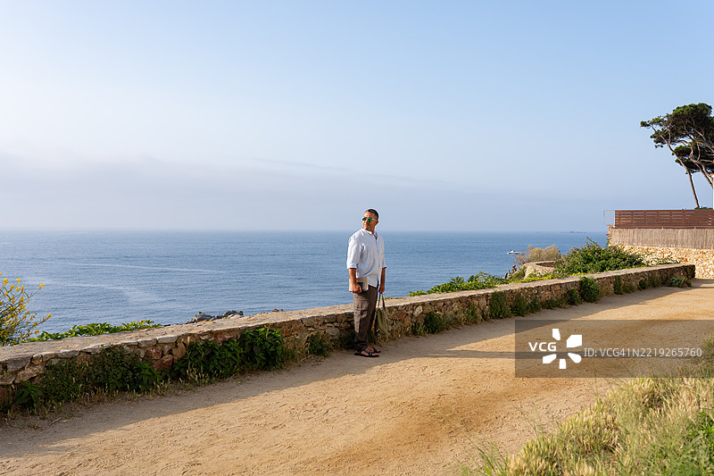 成熟的徒步旅行者站在海岸小径上，俯瞰广阔的海景，沉思宁静。图片素材