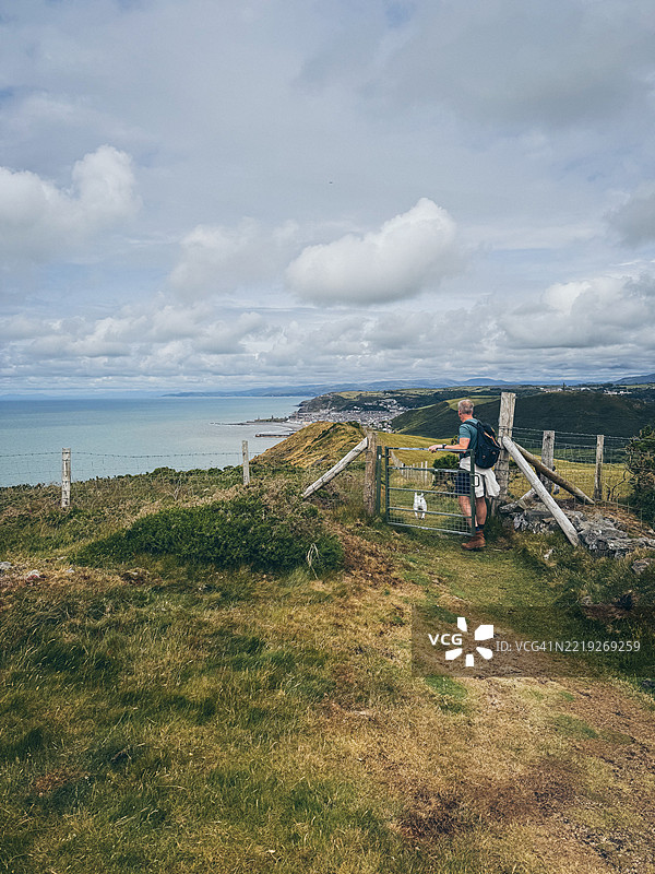 男子带着狗在前往阿伯里斯特威斯的塞雷迪根海岸小径上徒步旅行图片素材