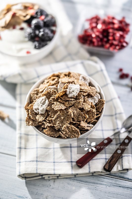 白色碗中盛着带有酸奶味的全谷物麦片，放在桌子上。图片素材