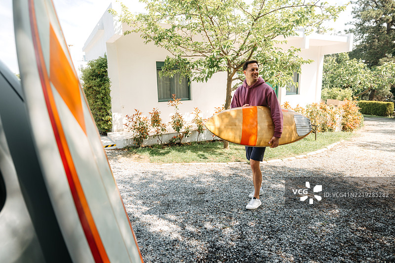 男子在后院提着冲浪板图片素材