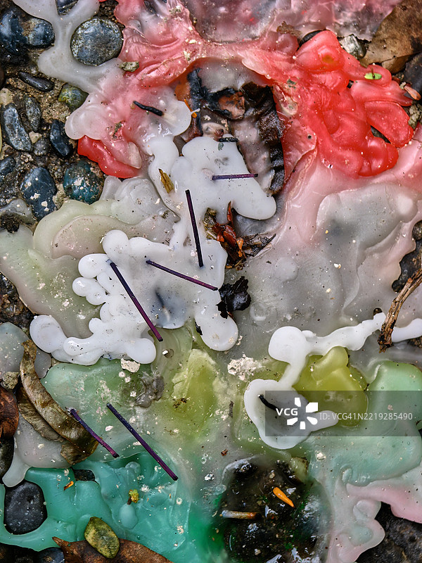 特写镜头展示了在粗糙的石头或混凝土表面上硬化的融化蜡烛蜡。图片素材