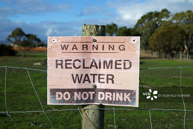 农场围栏柱上的标志：“警告：回收水。请勿饮用”图片素材
