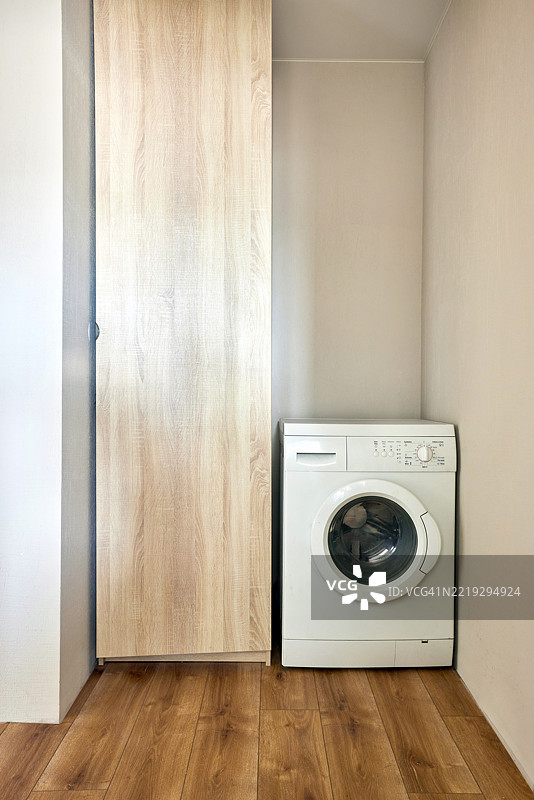 现代洗衣机位于简约风格的洗衣房，配有木地板。图片素材