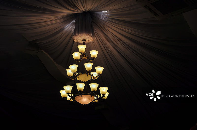 一个多层的吊灯，散发着温暖的黄色光芒。图片素材