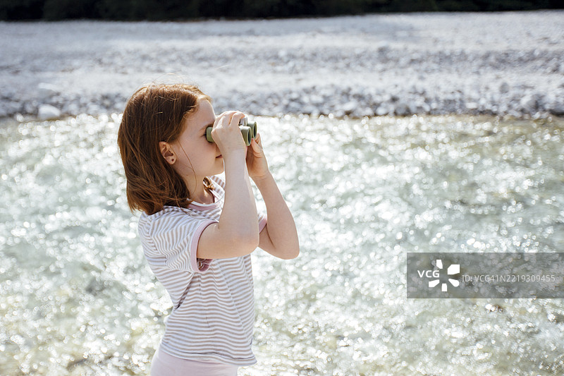 学龄女孩用望远镜探索山间河流图片素材