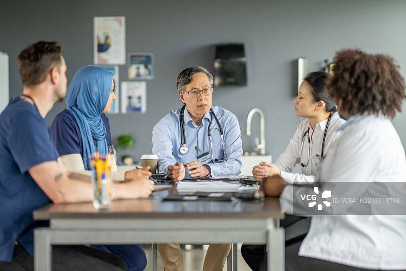 多元化的医疗专业人士围坐在桌子旁进行讨论图片素材