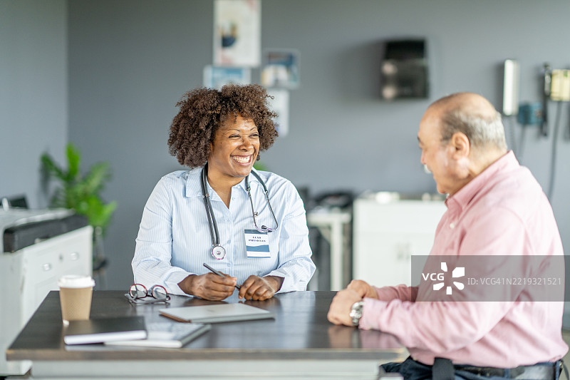 微笑的医生在现代办公室环境中与老年患者咨询图片素材