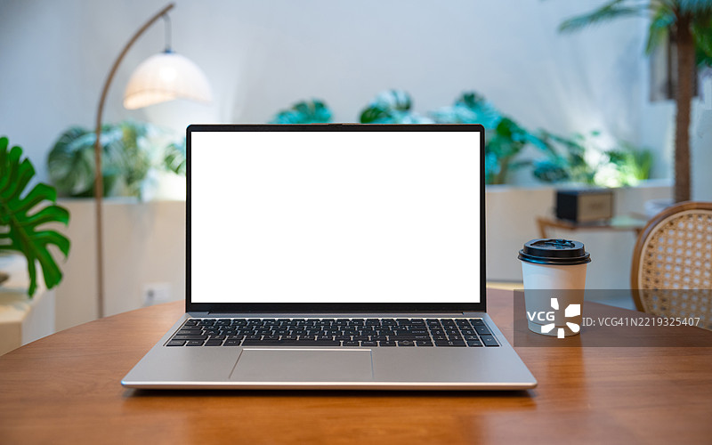咖啡馆背景下桌子上的笔记本电脑空白屏幕。咖啡店模糊背景中桌子上的空白屏幕笔记本电脑。图片素材