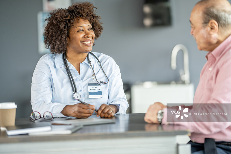 老年患者在诊所与微笑的女医生交谈图片素材