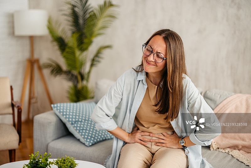 年轻女性在家中腹痛图片素材
