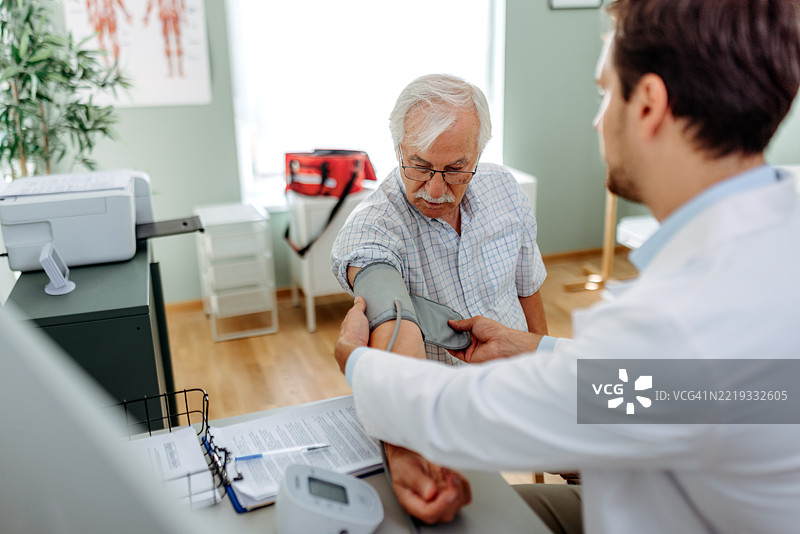 医生在诊所为老年男性患者测量血压图片素材