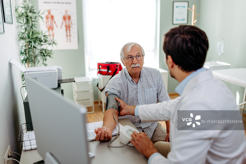 医生在诊所为老年男性患者测量血压图片素材