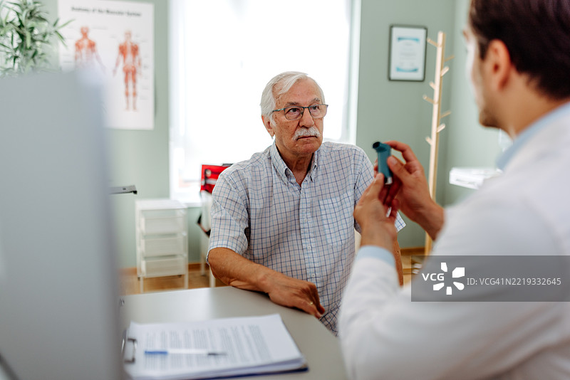 医生向老年男性演示如何使用哮喘吸入器图片素材