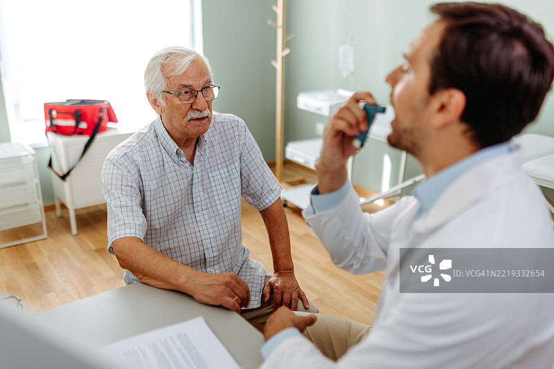 医生向老年男性演示如何使用哮喘吸入器图片素材