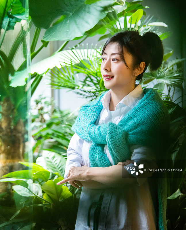 微笑的女性站在植物中间图片素材