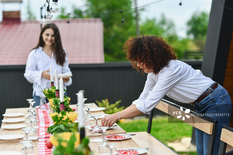 两位女性愉快而满意地布置花园派对的桌子图片素材