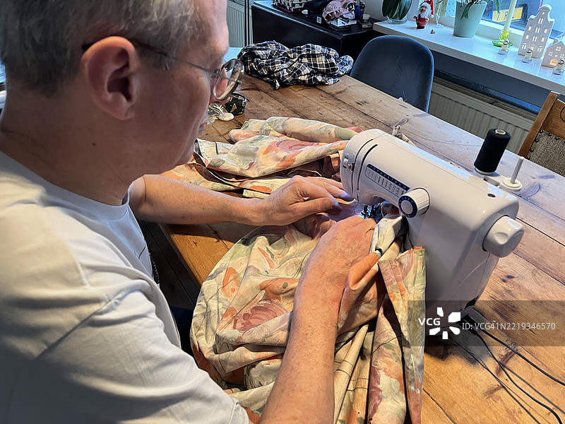 在阿姆斯特丹，荷兰，使用缝纫机在家缝制五彩缤纷的面料，庆祝拉丁美洲的圣诞和新年传统。图片素材