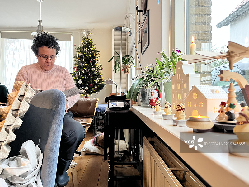 在阿姆斯特丹，荷兰，女人在圣诞树旁为“旧年”（Año viejo）切割手工艺品，庆祝拉丁美洲的圣诞和新年传统。图片素材