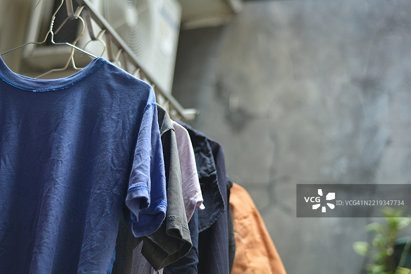 五颜六色的衬衫和裤子挂在晾衣架上晾晒。图片素材