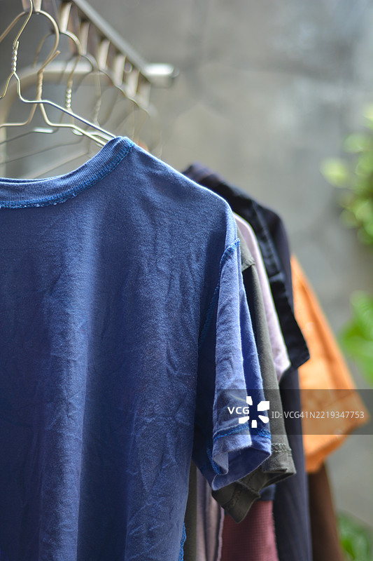 五颜六色的衬衫和裤子挂在晾衣架上晾晒。图片素材