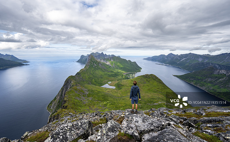 Øyfjorden和Mefjorden的峡湾景观，Fjordgård岬角的山脉，从Barden山上俯瞰，一名年轻男子远眺，挪威Senja，欧洲图片素材