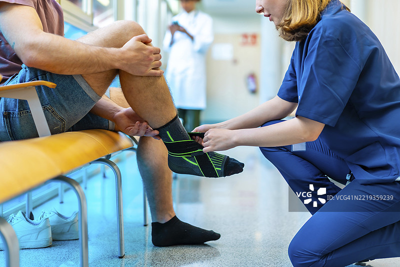 女护士在医院环境中为男病人受伤的脚踝包扎，提供支持和护理图片素材
