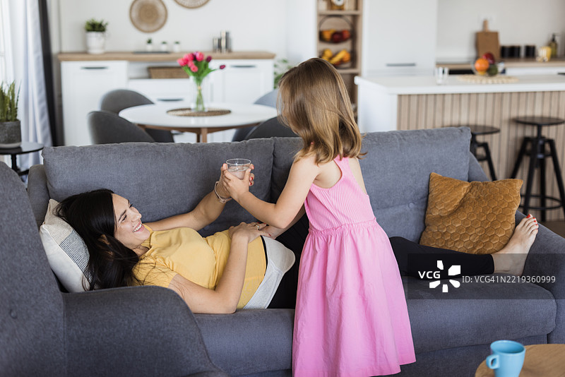 女孩给怀孕的母亲端水图片素材
