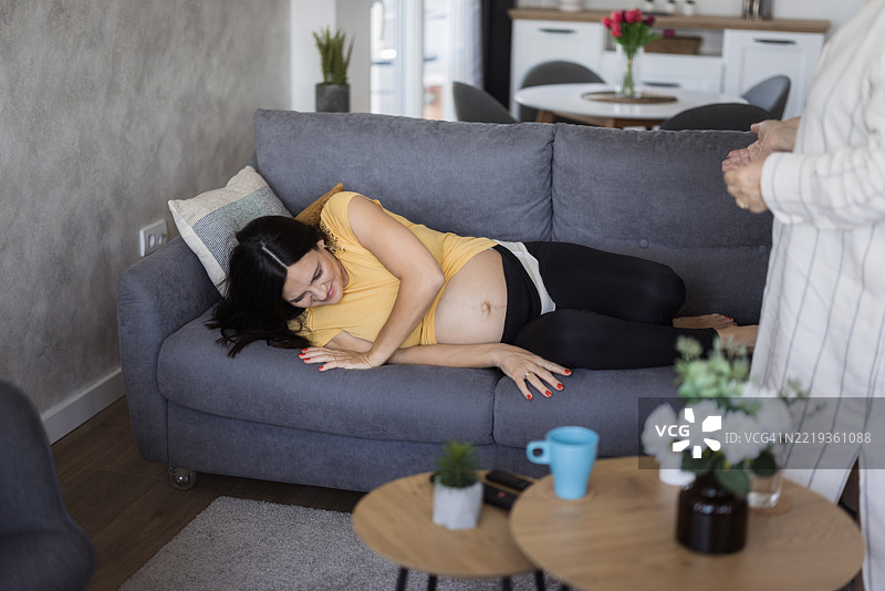 女性在床上帮助她怀孕的女儿起身图片素材